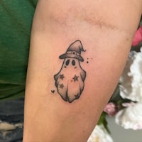 a small ghost tattoo on a woman's forearm