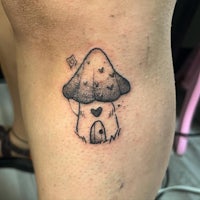 a small mushroom tattoo on a woman's thigh