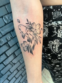 a black and white tattoo of a koi fish with flowers