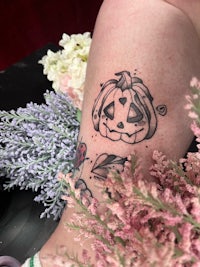 a tattoo of a pumpkin on a woman's leg