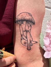 a tattoo of a woman sitting on a mushroom