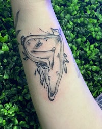 a tattoo of a clock on the forearm